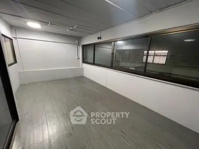 Spacious empty room with large windows and modern flooring, ideal for customization.