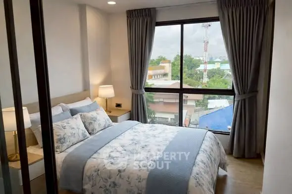 Cozy bedroom with large window offering a scenic view, featuring elegant bedding and modern decor.