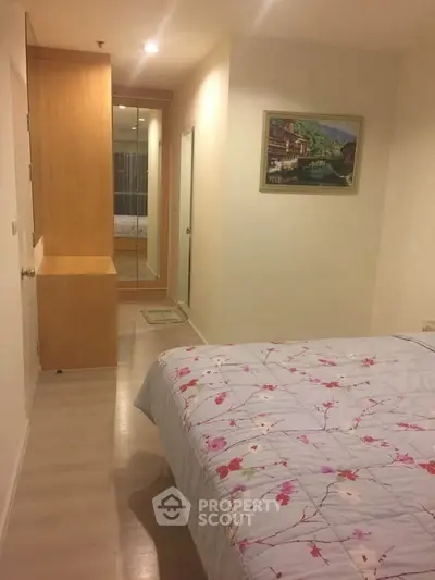 Cozy bedroom with floral bedding and mirrored wardrobe in modern apartment.