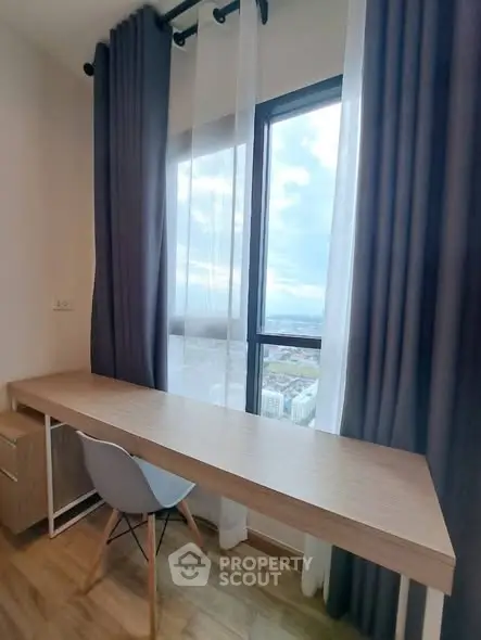 Modern study area with large window and stylish desk in high-rise apartment.