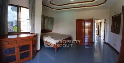 Spacious bedroom with wooden furniture and large windows for natural light.