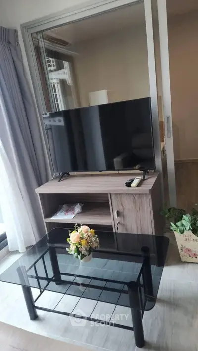 Modern living room with sleek TV stand and glass coffee table, perfect for cozy entertainment.