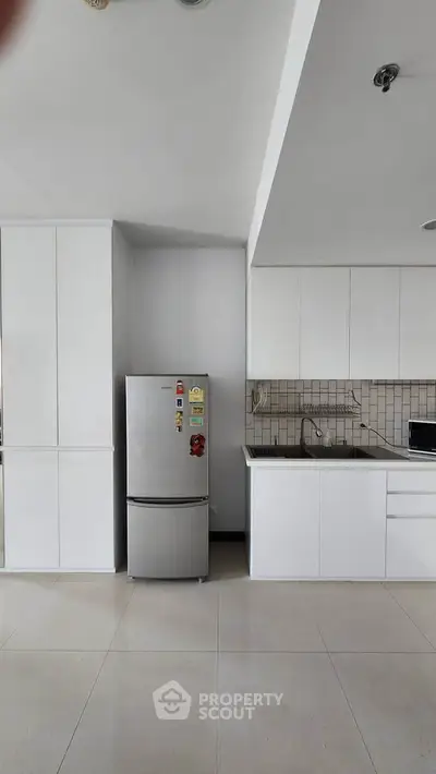 Modern kitchen with sleek white cabinets and stainless steel fridge