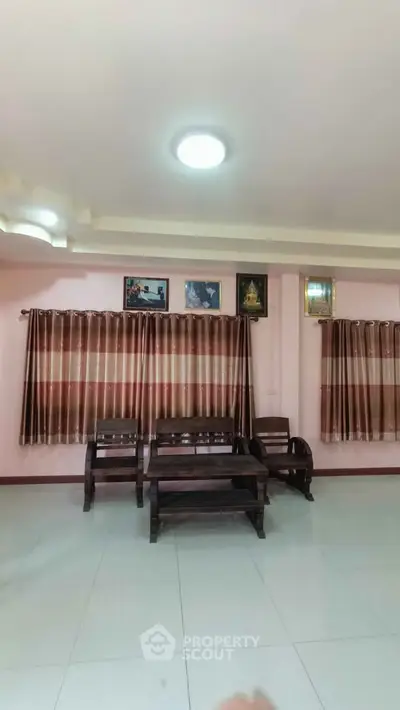 Spacious living room with elegant wooden furniture and large windows.