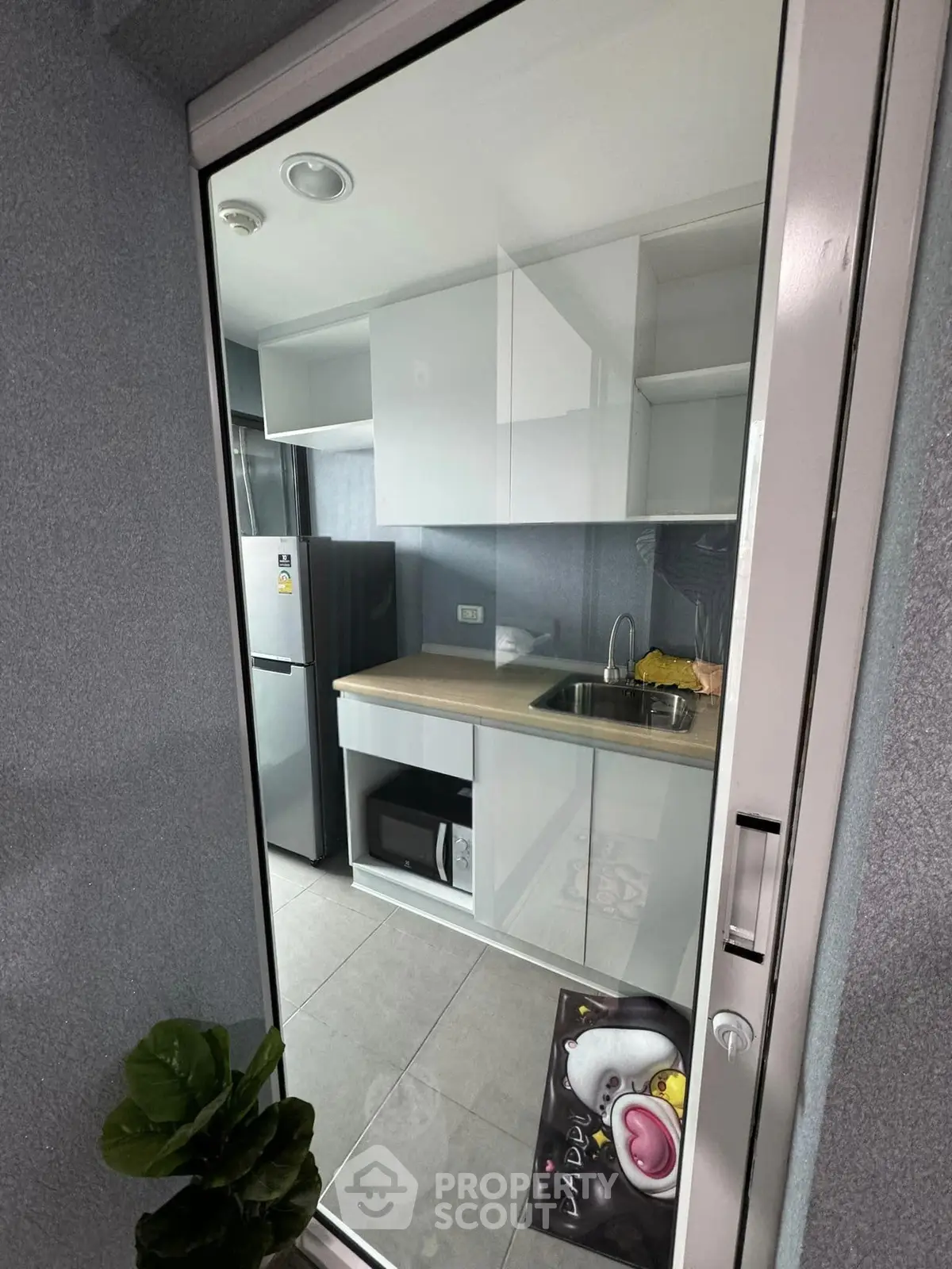 Modern kitchen with sleek cabinetry, stainless steel fridge, and microwave, perfect for urban living.