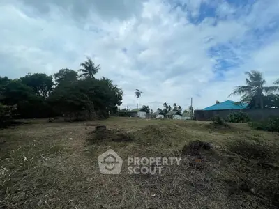 Spacious land plot with lush greenery and distant houses, perfect for development opportunities.
