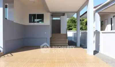 Modern residential entrance with spacious driveway and steps leading to the main door.