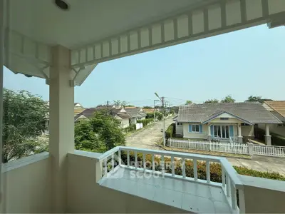 Charming suburban view from a cozy balcony overlooking a quiet residential street with lush greenery.