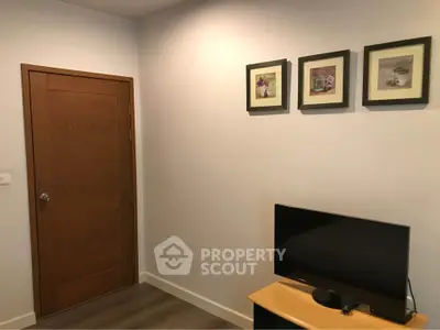 Cozy interior with wooden door and wall-mounted art, featuring a compact TV setup.