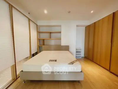 Spacious bedroom with wooden flooring and ample storage in modern apartment