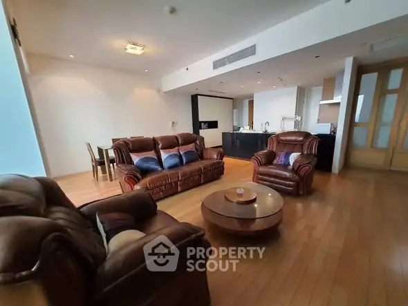 Spacious living room with leather sofas and open kitchen layout
