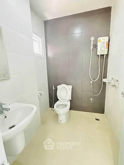 Modern bathroom with sleek fixtures and neutral tiles, featuring a shower and toilet.