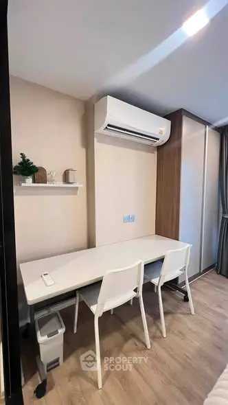 Modern study area with sleek desk, chairs, and air conditioning in a stylish apartment.