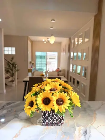 Charming living room with sunflowers on marble table, modern decor, and bright ambiance.