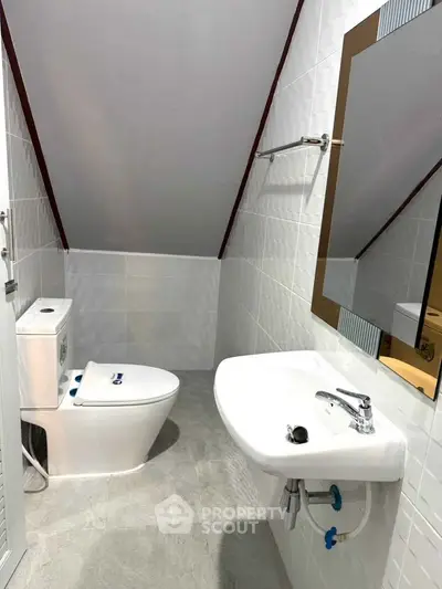 Compact attic bathroom with modern fixtures and sloped ceiling design.