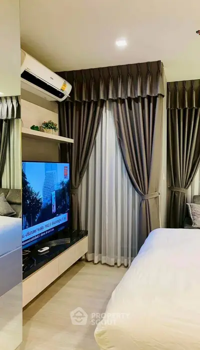 Modern bedroom with stylish curtains, wall-mounted TV, and air conditioning unit.