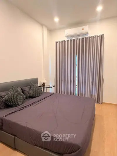 Modern bedroom with stylish decor and air conditioning, featuring a cozy bed and elegant curtains.