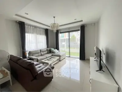 Spacious living room with modern decor and garden view, featuring large windows and comfortable seating.