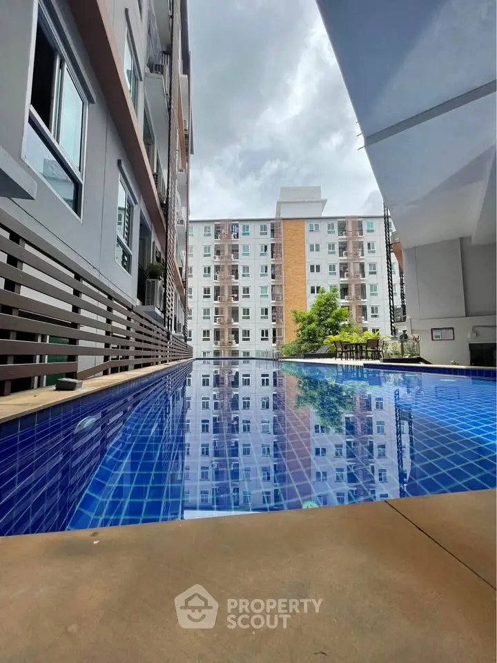 Modern apartment complex with a stunning outdoor pool reflecting the sky and buildings.