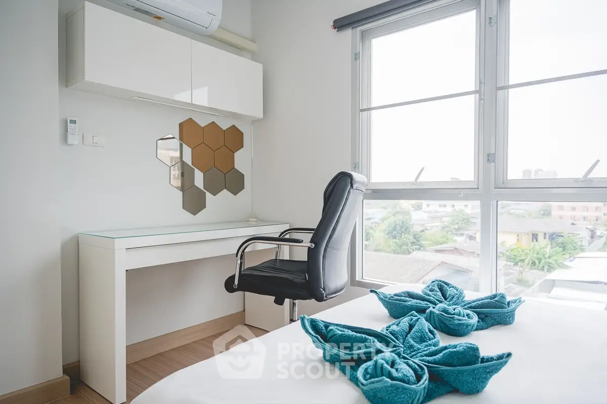 Modern bedroom with stylish desk and city view, featuring elegant decor and natural light.