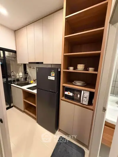 Modern kitchen with sleek cabinetry, black fridge, and built-in microwave, perfect for urban living.