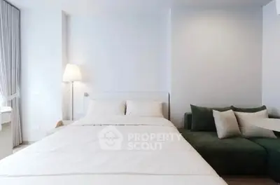 Modern bedroom with cozy bed and stylish sofa in a bright, minimalist design.