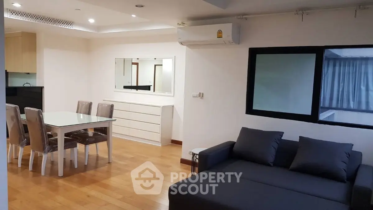 Spacious modern living room with dining area, featuring sleek furniture and large windows for natural light.