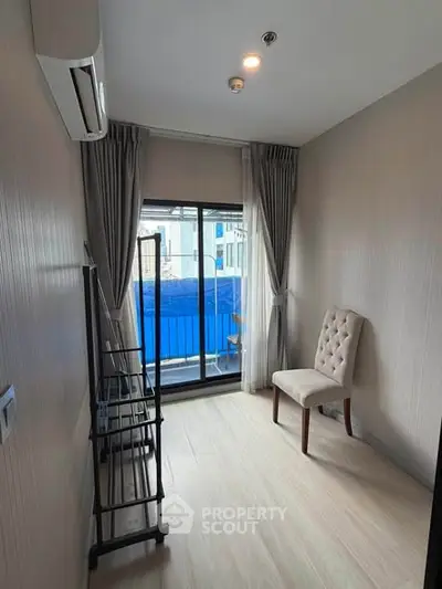 Cozy small room with balcony access, featuring elegant chair and modern air conditioning.