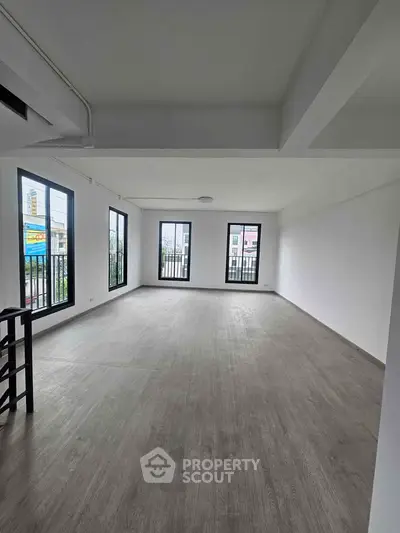 Spacious empty room with large windows and wooden flooring, perfect for customization.