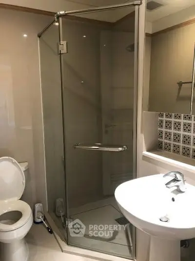 Modern bathroom with glass shower enclosure and sleek fixtures.