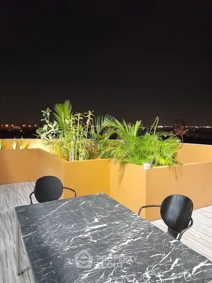 Stylish rooftop terrace with modern furniture and lush greenery, perfect for evening relaxation.