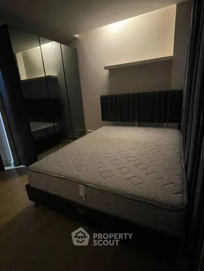 Cozy bedroom with modern design featuring a comfortable bed and sleek mirrored wardrobe.