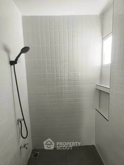 Minimalist bathroom with white tiles and modern showerhead