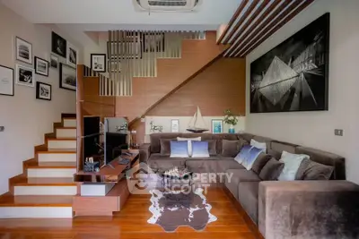 Stylish living room with modern decor, sectional sofa, and unique staircase design.