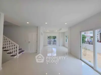 Spacious modern living room with glossy white tiles and large windows for natural light.