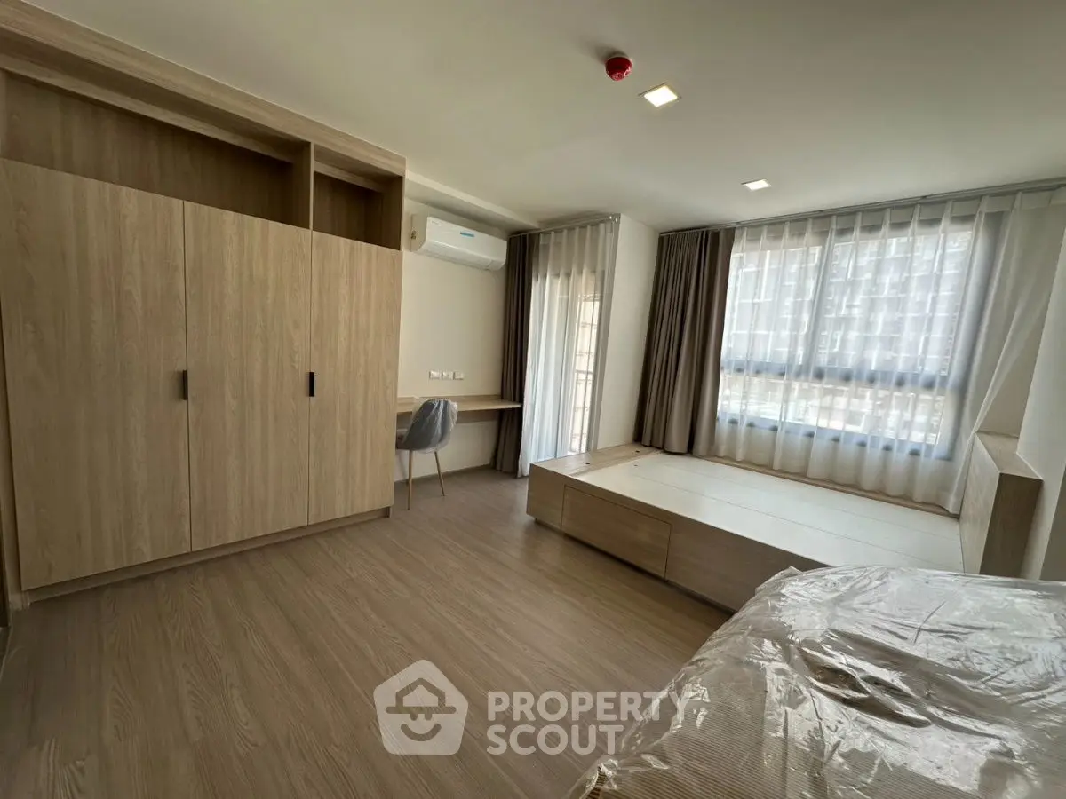 Spacious modern bedroom with large windows and built-in storage in a stylish apartment.