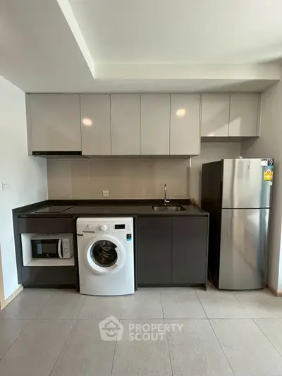 Modern kitchen with sleek appliances including washing machine and fridge