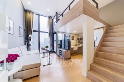 Modern loft-style living room with high ceilings and elegant staircase