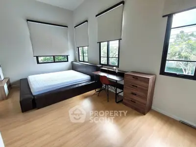 Spacious bedroom with large windows and modern furnishings, offering a serene view and ample natural light.