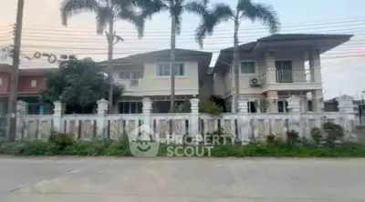 Charming two-story house with palm trees and a gated fence in a serene neighborhood.