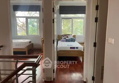 Spacious bedroom with wooden flooring and large windows offering natural light and serene views.