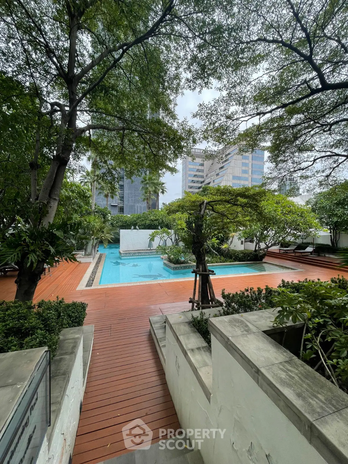 Luxurious urban pool surrounded by lush greenery and modern architecture.