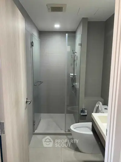 Modern bathroom with glass shower and sleek fixtures in contemporary apartment.