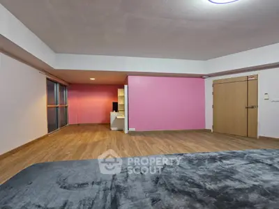 Spacious bedroom with wooden flooring and pink accent wall