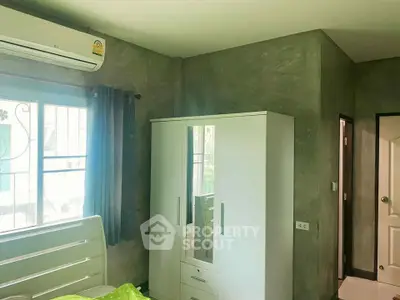 Cozy bedroom with modern wardrobe and air conditioning, featuring natural light from a large window.