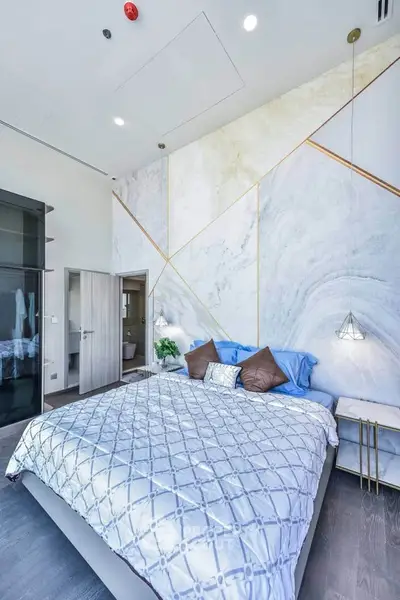 Luxurious bedroom with modern decor and high ceiling, featuring elegant lighting and stylish wall design.