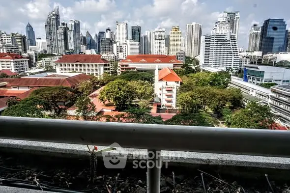 Stunning cityscape view from a high-rise balcony overlooking lush greenery and urban skyline.