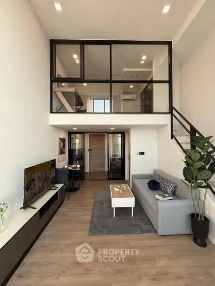 Modern loft-style living room with high ceilings and mezzanine, featuring sleek furniture and stylish decor.