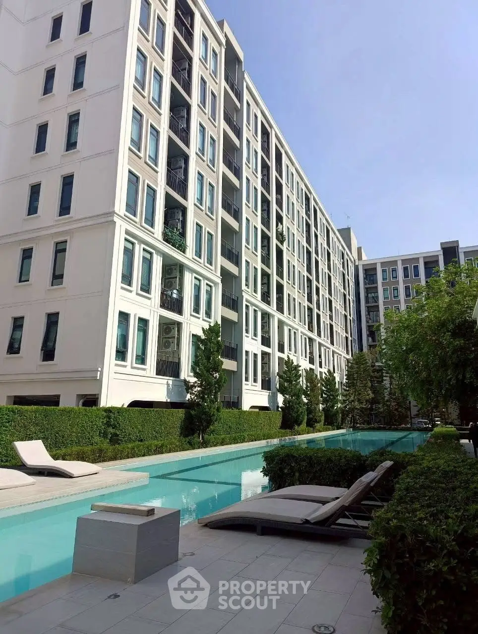 Modern apartment building with pool and lush greenery, perfect for urban living.