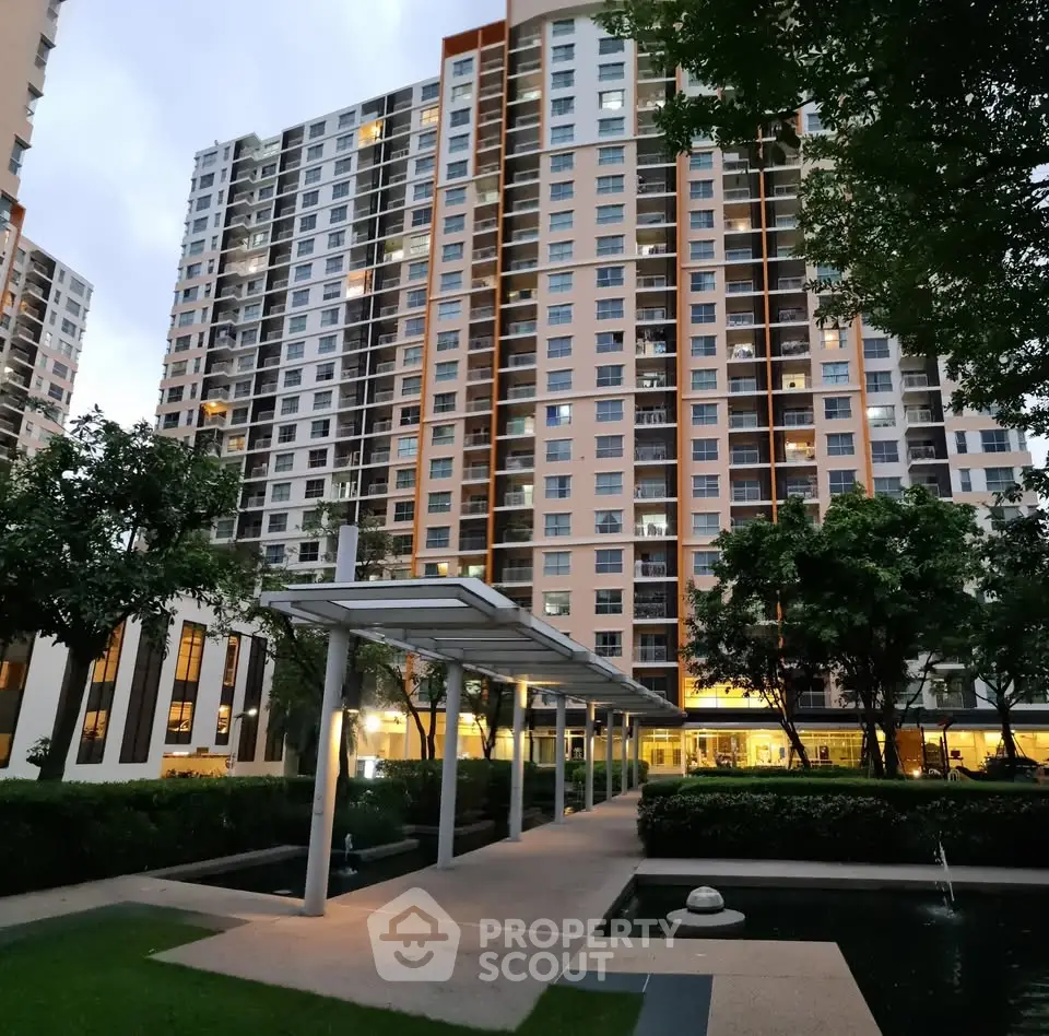 Modern high-rise apartment building with landscaped garden and walkway at dusk.